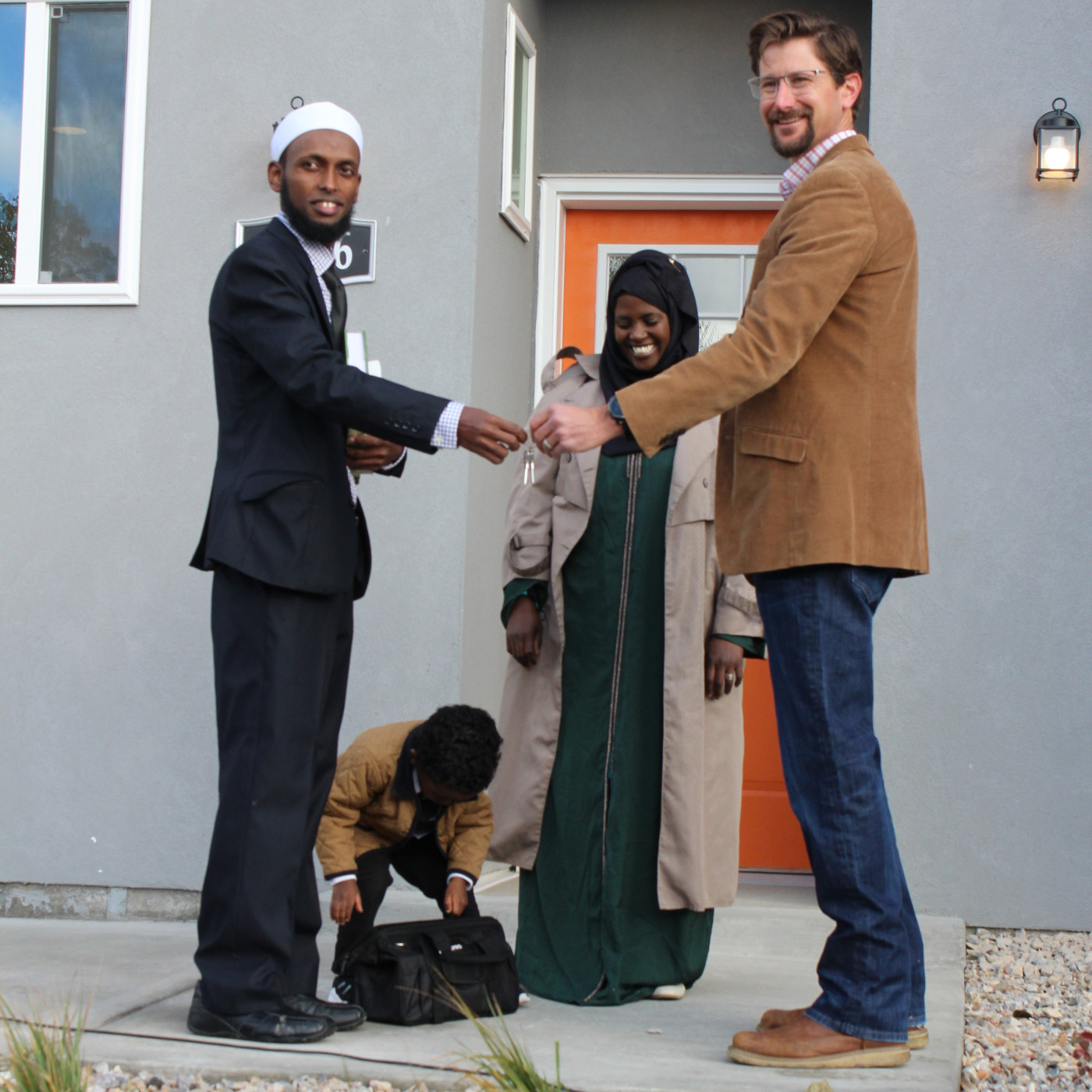 Man handing a set of house keys to a family. 